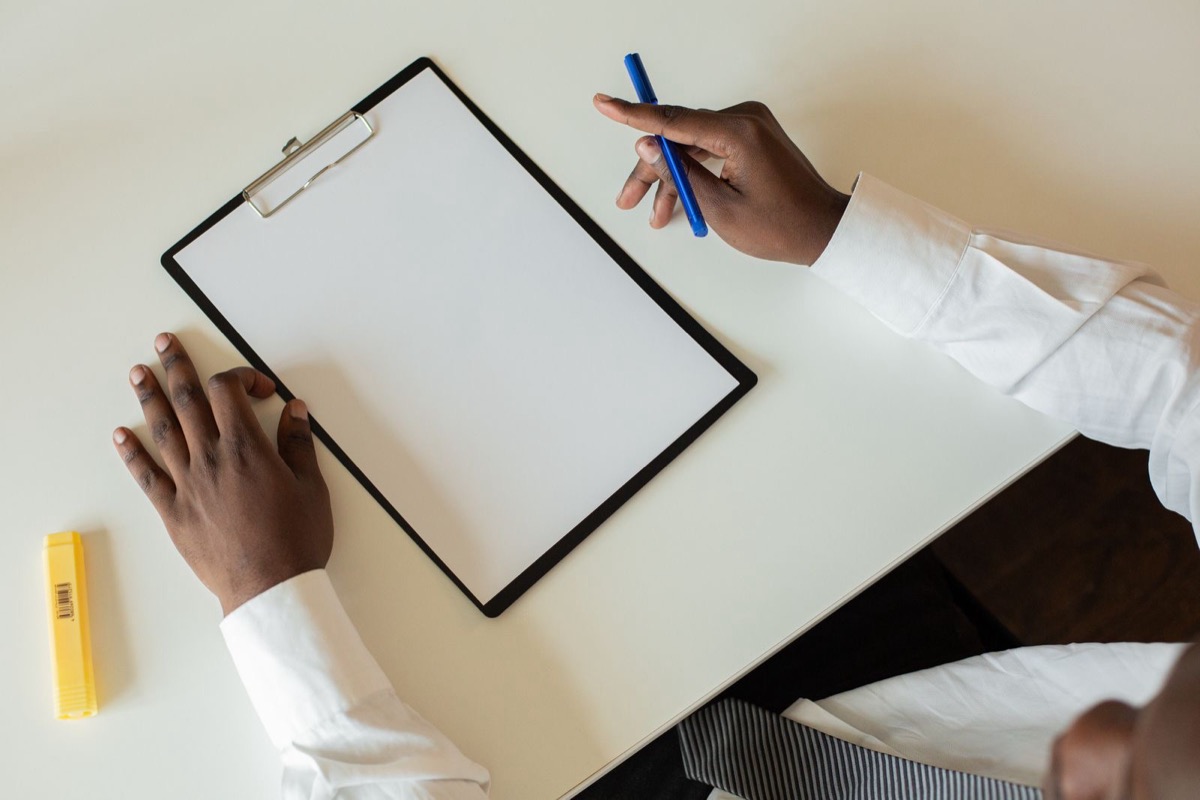 Hands over a blank clipboard, one holding a pen