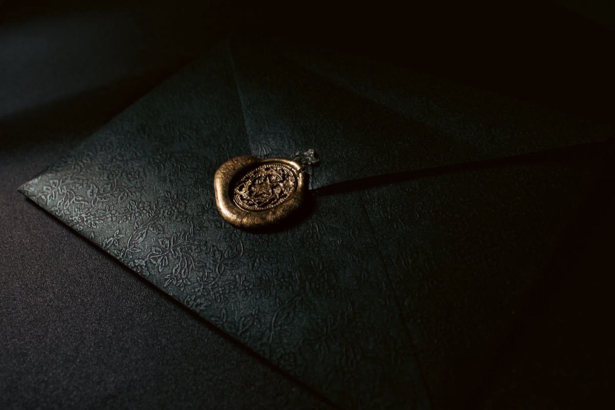 A dark envelope closed with a gold wax seal