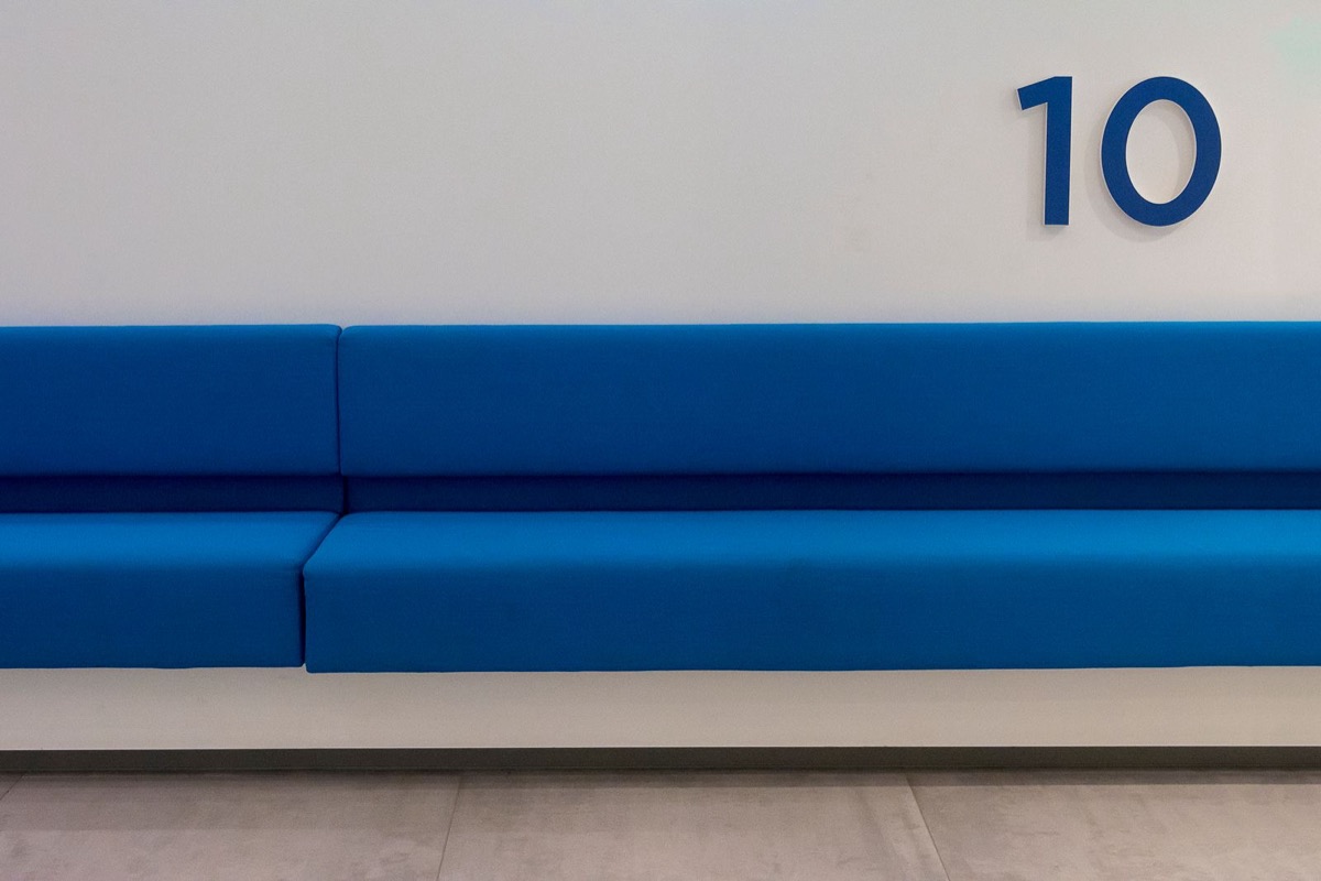 A blue bench below a large number on a white wall
