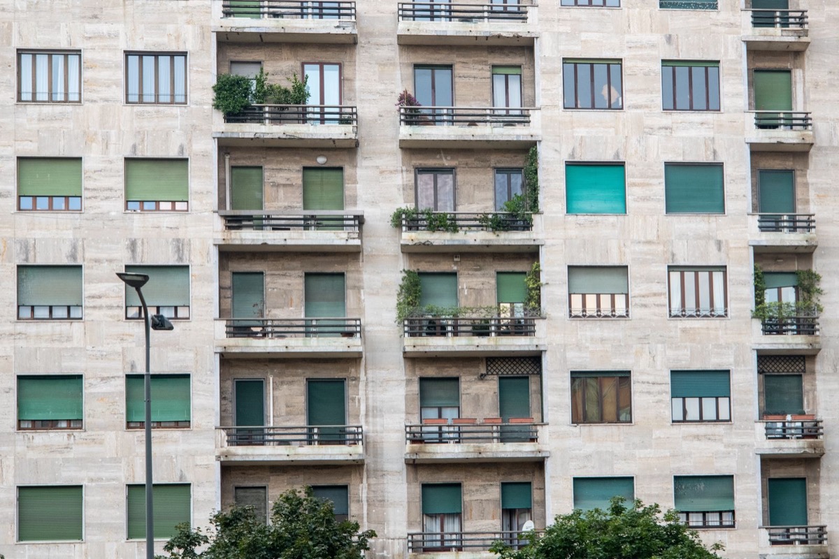 The facade of a residential building in Milan with shutters and small balconies