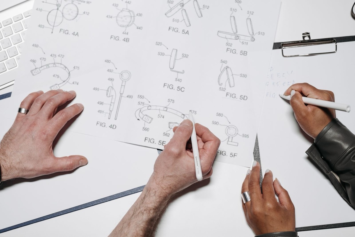 Hands drawing numbered technical figures on a sheet