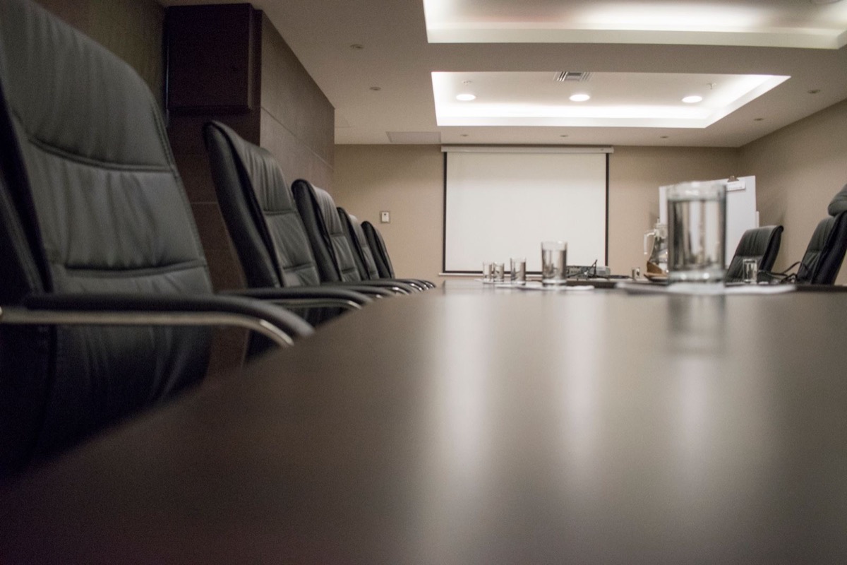 An empty boardroom table lined with leather chairs