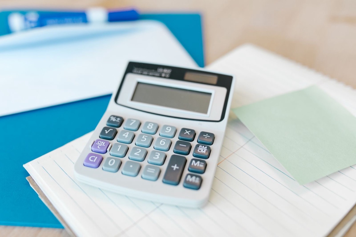 A calculator on a ruled notepad beside a blue folder
